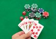 A close-up of playing cards and poker chips on a green felt surface.