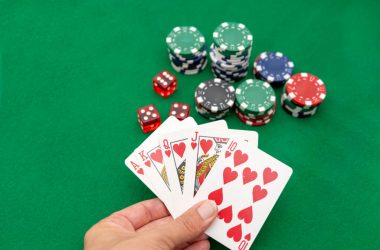 A close-up of playing cards and poker chips on a green felt surface.