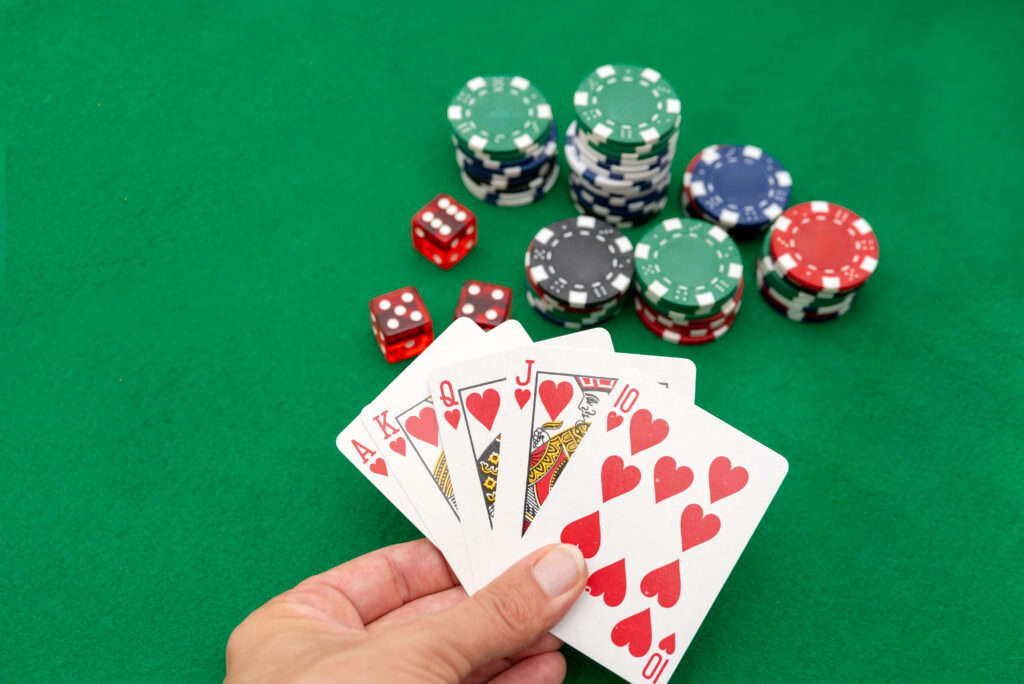 A close-up of playing cards and poker chips on a green felt surface.